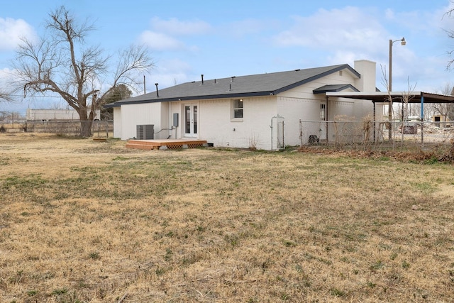 back of house featuring a yard, central AC, fence, and brick siding