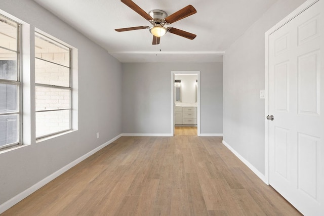 unfurnished bedroom featuring light wood-type flooring, ensuite bath, a ceiling fan, and baseboards