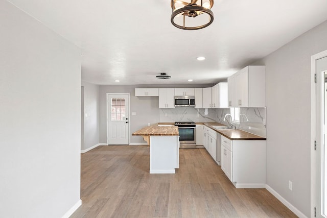 kitchen with white cabinets, a kitchen island, a sink, stainless steel appliances, and backsplash