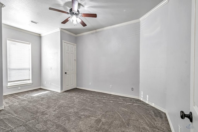 spare room featuring baseboards, visible vents, dark colored carpet, and ornamental molding