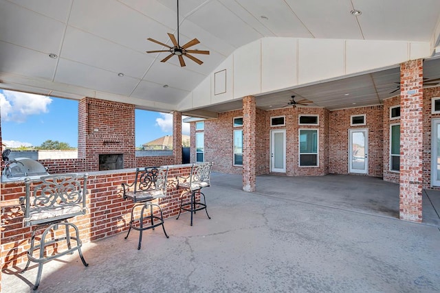 view of patio / terrace with ceiling fan, an outdoor brick fireplace, and an outdoor kitchen