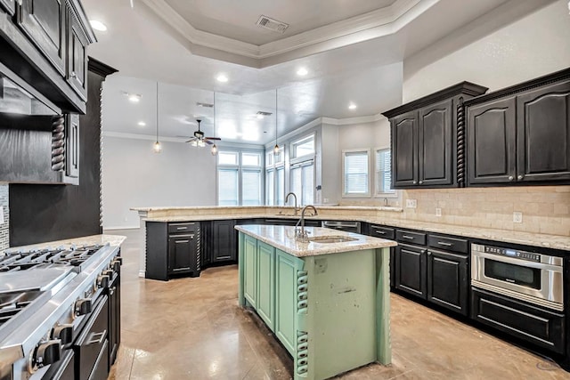 kitchen featuring visible vents, decorative backsplash, an island with sink, light stone counters, and pendant lighting