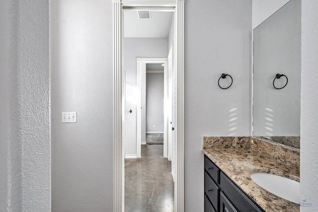 bathroom featuring a textured wall, concrete floors, visible vents, vanity, and baseboards