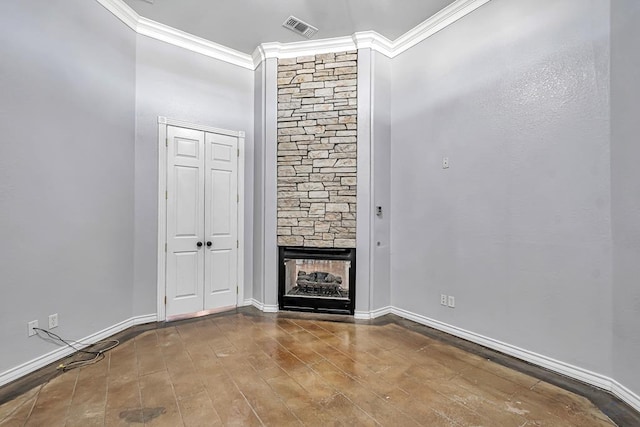 unfurnished living room with ornamental molding, visible vents, a fireplace, and wood finished floors