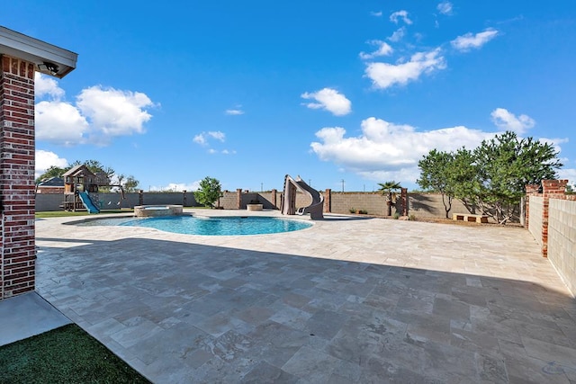 view of pool with a water slide, a playground, a fenced backyard, a pool with connected hot tub, and a patio area