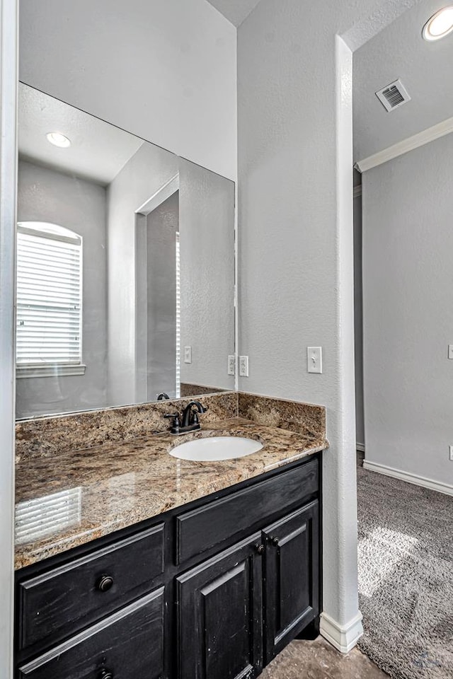 bathroom featuring a textured wall, recessed lighting, visible vents, vanity, and baseboards