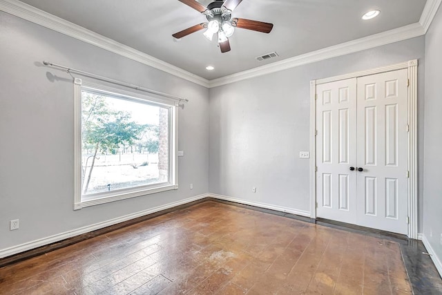 spare room featuring ceiling fan, visible vents, baseboards, ornamental molding, and dark wood-style floors