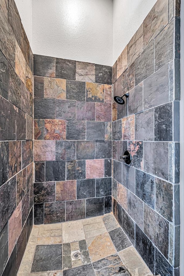 bathroom with tiled shower and stone tile flooring