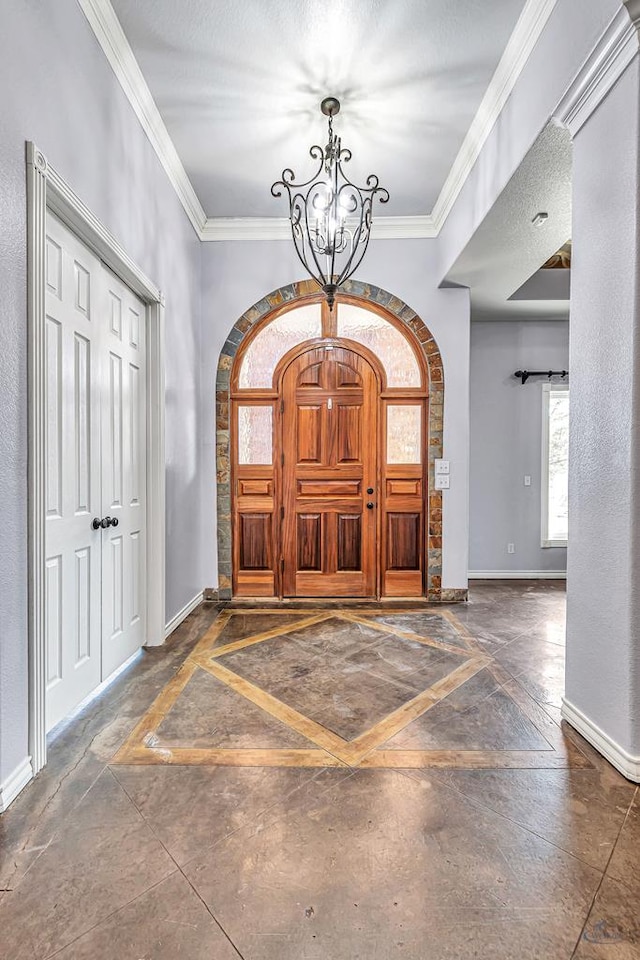 foyer entrance featuring crown molding, arched walkways, a notable chandelier, and baseboards