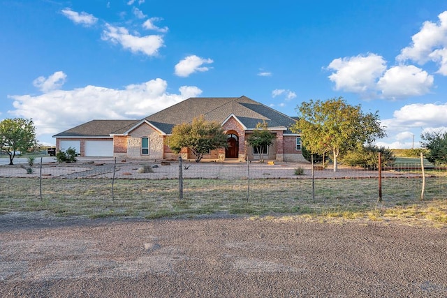 view of front of house featuring a fenced front yard, brick siding, and an attached garage