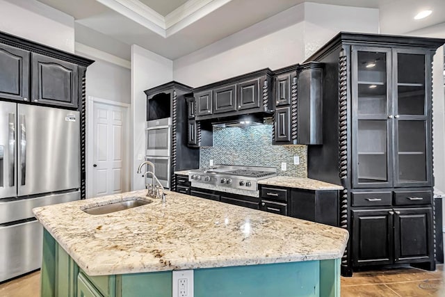 kitchen with crown molding, appliances with stainless steel finishes, glass insert cabinets, a sink, and an island with sink