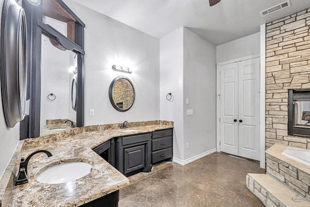 bathroom featuring double vanity, tiled bath, a sink, and visible vents