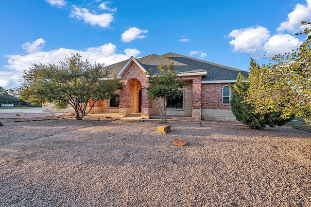 ranch-style home featuring brick siding and a shingled roof