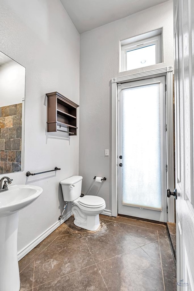 bathroom with toilet, baseboards, and a sink