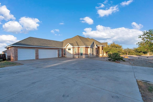 view of front of house featuring a shingled roof, concrete driveway, brick siding, and an attached garage