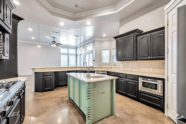 kitchen featuring crown molding, light stone counters, a kitchen island with sink, and decorative light fixtures