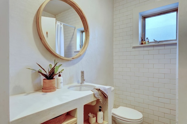 bathroom featuring toilet, sink, and a shower with shower curtain