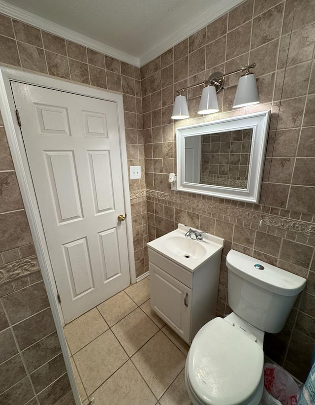 bathroom featuring tile patterned floors, ornamental molding, vanity, tile walls, and toilet