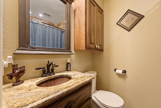 bathroom featuring walk in shower, vanity, a textured ceiling, and toilet