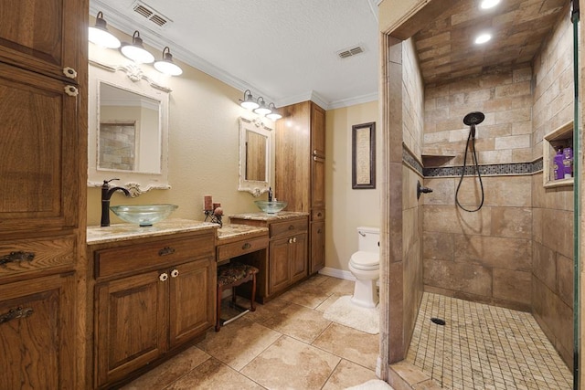 bathroom featuring tile patterned flooring, tiled shower, toilet, vanity, and ornamental molding