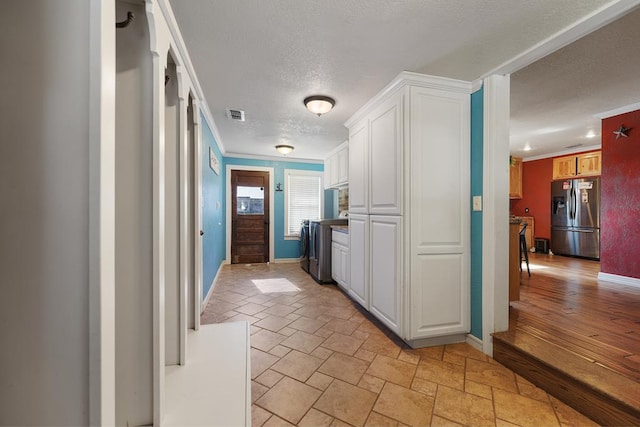 kitchen featuring stainless steel refrigerator with ice dispenser, light hardwood / wood-style flooring, ornamental molding, a textured ceiling, and white cabinetry