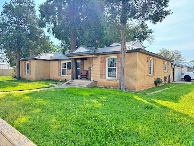 ranch-style home with a garage, brick siding, metal roof, and a front lawn