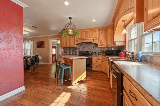 kitchen featuring a kitchen breakfast bar, dark hardwood / wood-style flooring, a kitchen island, and black appliances