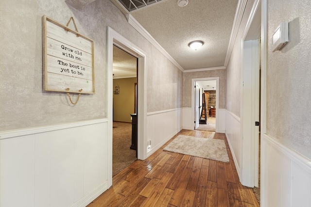 corridor featuring wood-type flooring, a textured ceiling, and ornamental molding