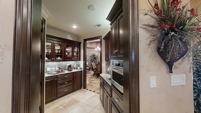 kitchen featuring backsplash, dark brown cabinetry, and crown molding