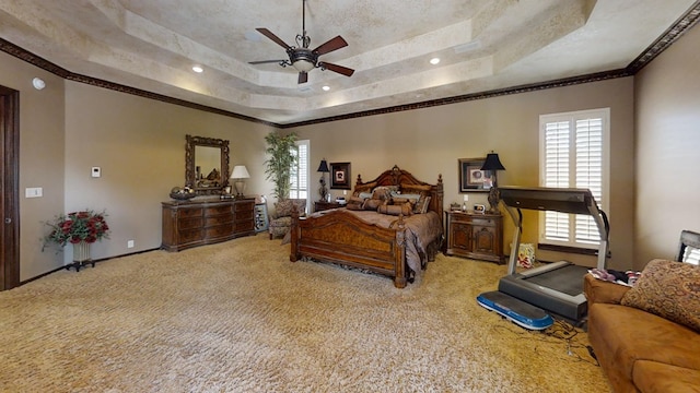 carpeted bedroom featuring ceiling fan, crown molding, and a tray ceiling