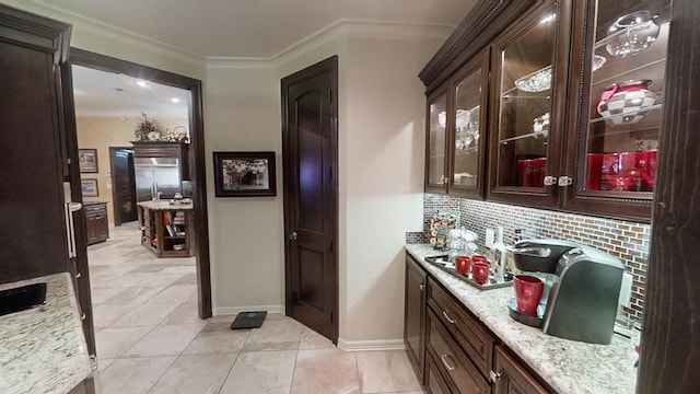 bar featuring decorative backsplash, light stone counters, light tile patterned floors, and crown molding