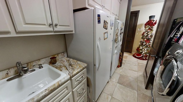 kitchen with white cabinetry, sink, white refrigerator, washer / clothes dryer, and ornamental molding