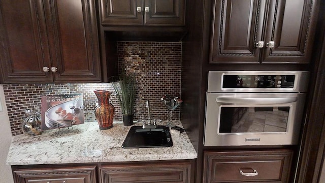 kitchen featuring dark brown cabinets, stainless steel oven, and tasteful backsplash