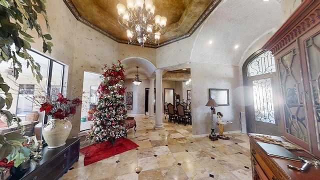 foyer with a high ceiling, ornate columns, and a notable chandelier