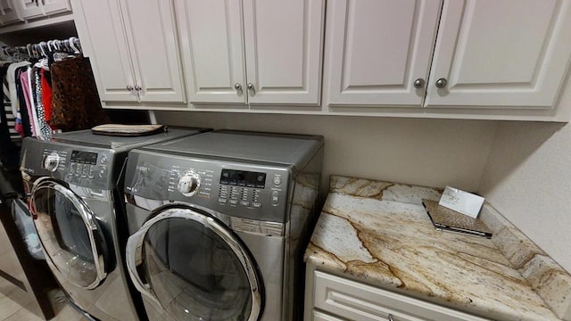 clothes washing area featuring cabinets and washing machine and clothes dryer