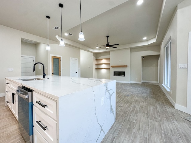 kitchen featuring light stone counters, sink, a spacious island, and decorative light fixtures