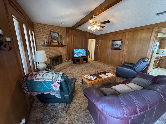 carpeted living room featuring visible vents, wooden walls, a brick fireplace, lofted ceiling with beams, and a textured ceiling