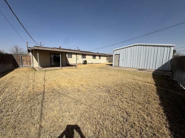 view of yard with a gate, an outdoor structure, and fence