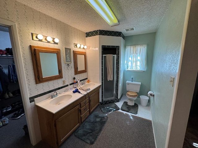 full bathroom featuring wallpapered walls, a textured ceiling, and a sink