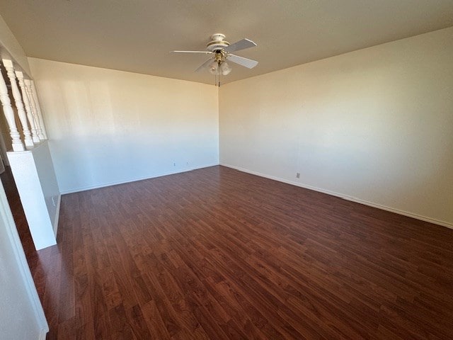 empty room with ceiling fan, baseboards, and dark wood-type flooring