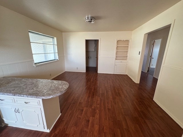 interior space with built in shelves and dark wood finished floors