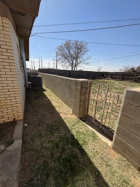 view of yard with central AC and fence