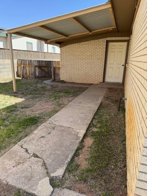 entrance to property featuring brick siding and fence