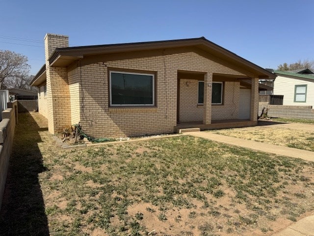 back of property with brick siding, a chimney, fence, and a lawn