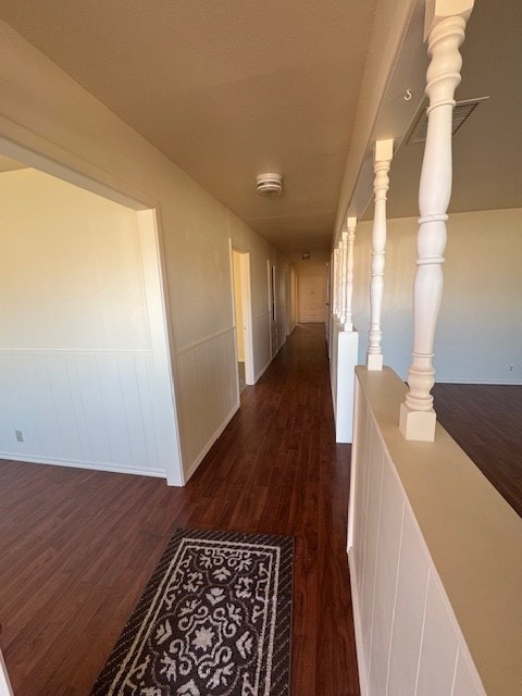 hall featuring dark wood-style floors and a wainscoted wall