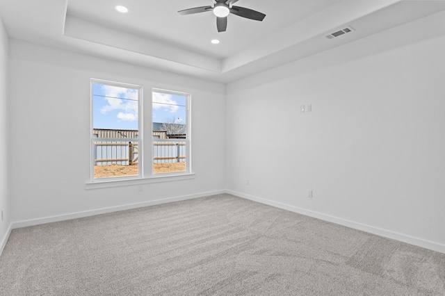 carpeted empty room featuring a raised ceiling and ceiling fan