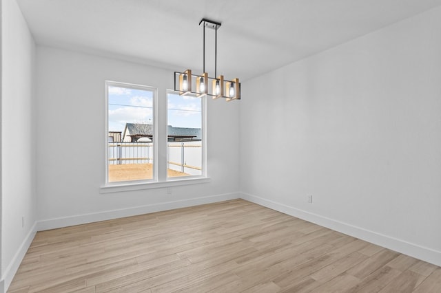 spare room with a notable chandelier and light hardwood / wood-style floors