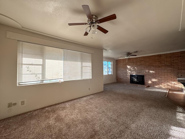 unfurnished living room with carpet flooring, ceiling fan, brick wall, and a brick fireplace