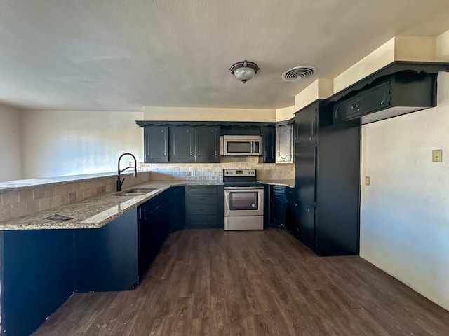 kitchen featuring kitchen peninsula, tasteful backsplash, light stone counters, stainless steel appliances, and sink