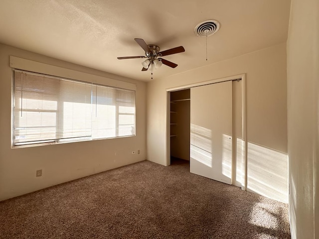 unfurnished bedroom with multiple windows, carpet floors, a closet, and ceiling fan